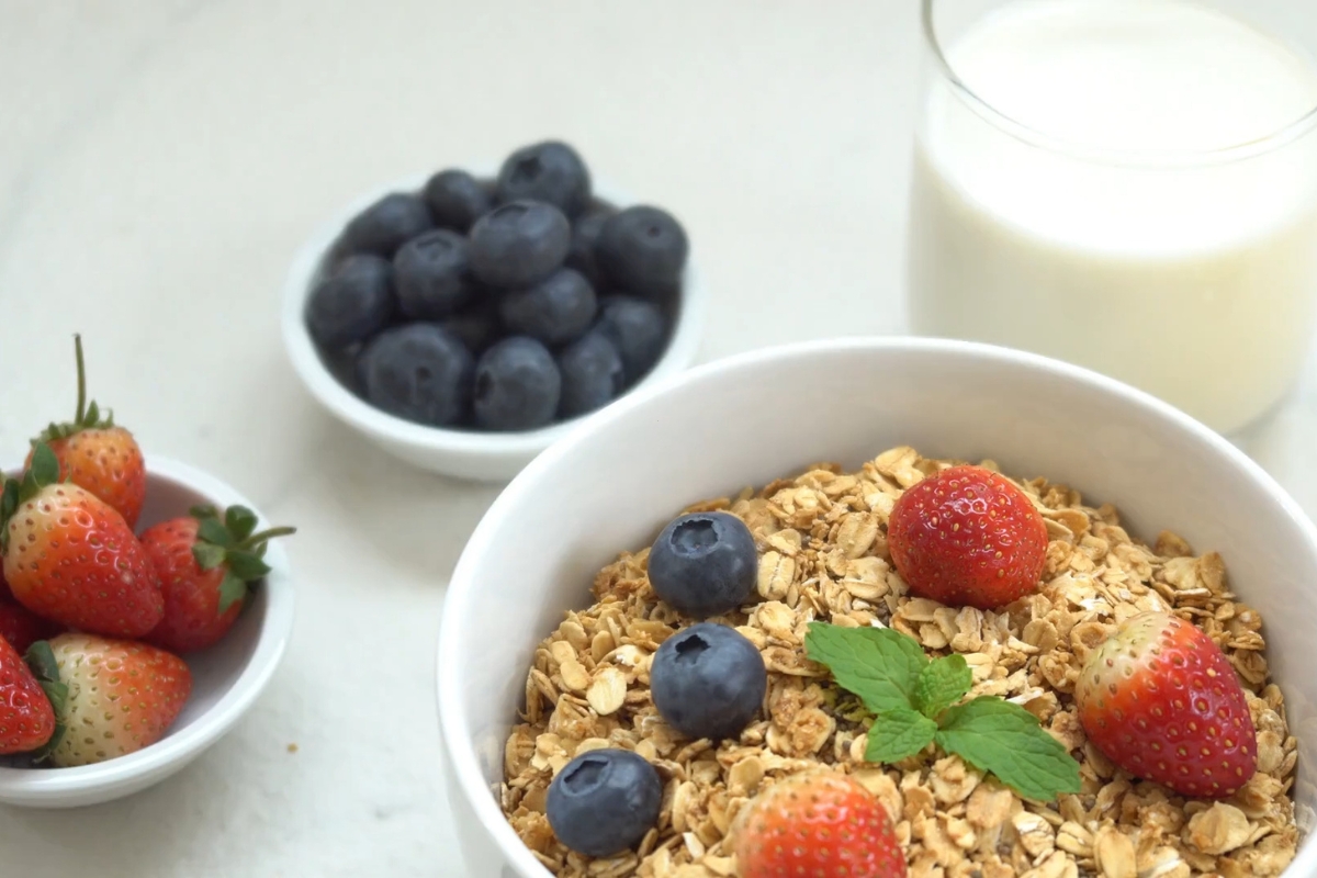 prikaz pahuljica, borovnica, mleka i jagoda u činijama na stolu